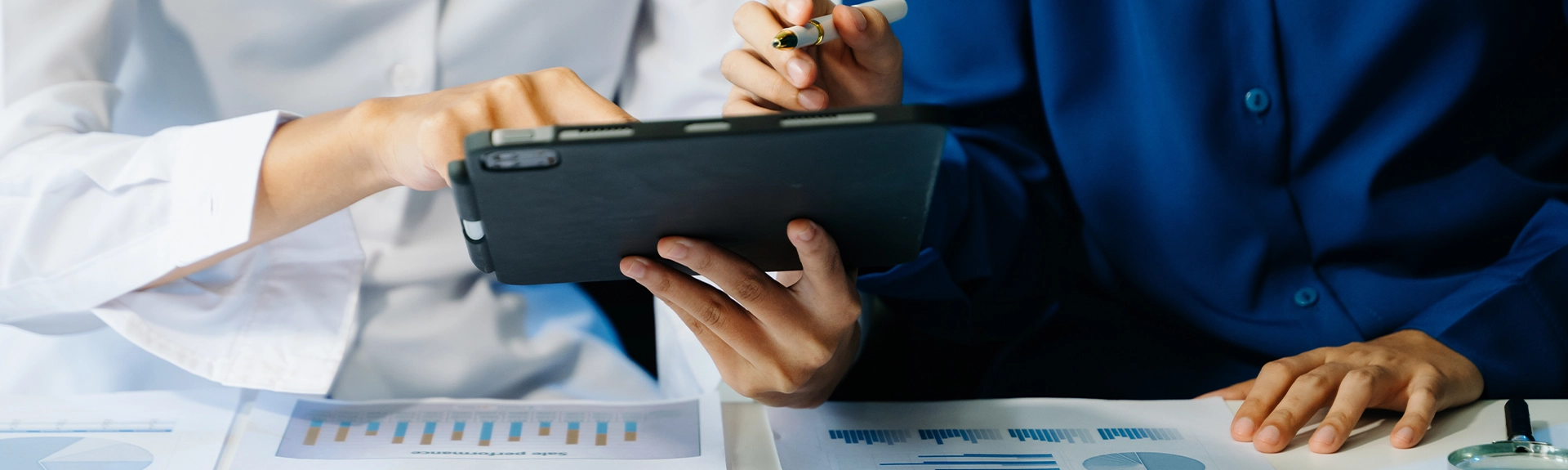 Two people manipulating a tablet.