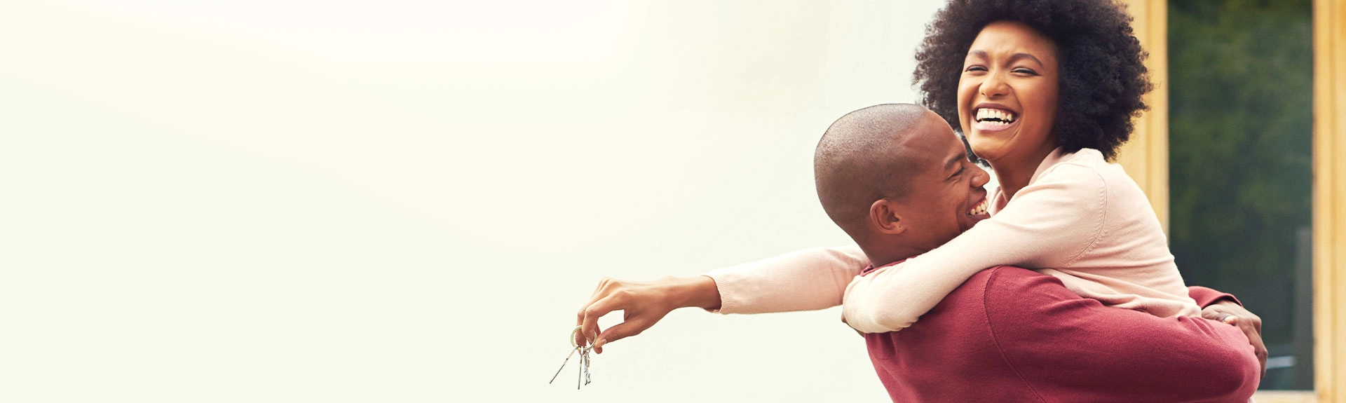 A woman holding keys to a new home and hugging her significant other.