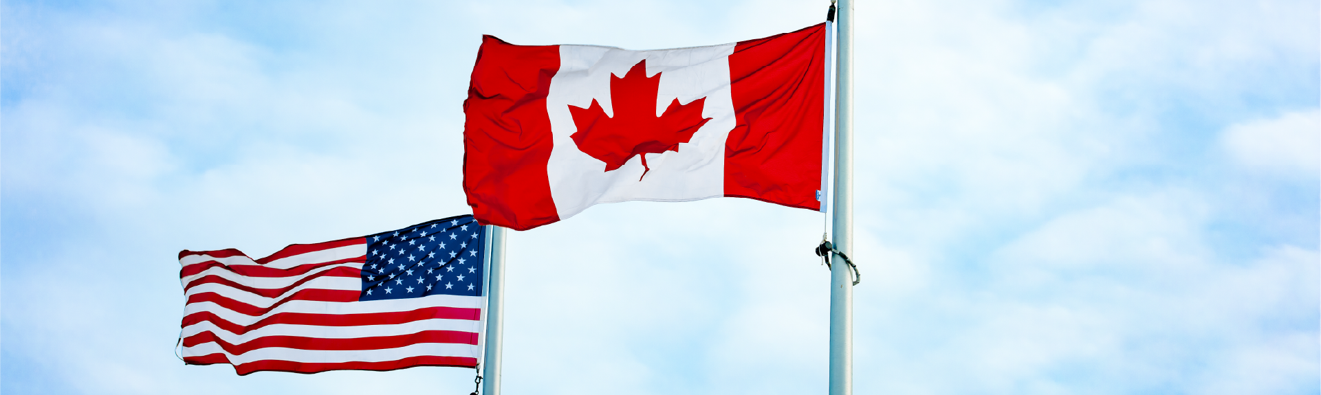 Canadian and American flags on a slightly cloudy day